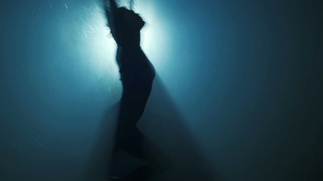 Young sports woman dancing with ring silhouette. Water and smoke effects for soft abstract blurred motion. Slow motion.
