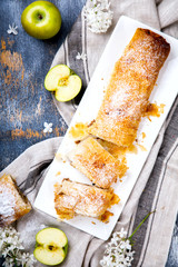 Strudel Apple and sugar powder. Biscuit from the puffed Test on the Gray Background. Dessert with...