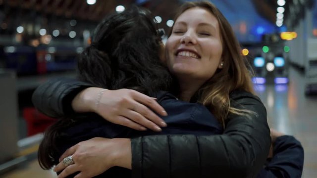 Happy girl hug her friend on arriving at the train station