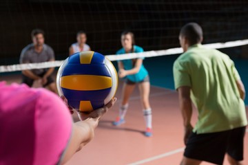 Cropped hand of player with teammates holding volleyball