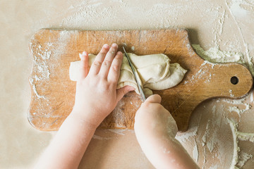 A child cuts the raw dough