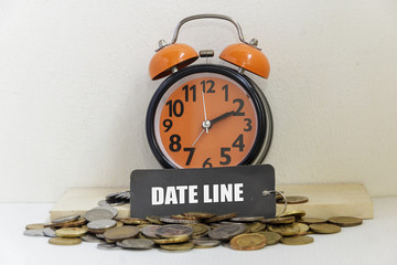 Alarm clock and coins the word "DATE LINE" - business concept