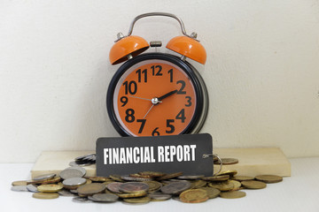 Alarm clock and coin with word "FINANCIAL REPORT" - business concept