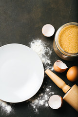 Baking or cooking background with flour, sugar, kitchen tools and eggs, top view
