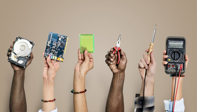 Group of hands holding computer electronics parts on brown background