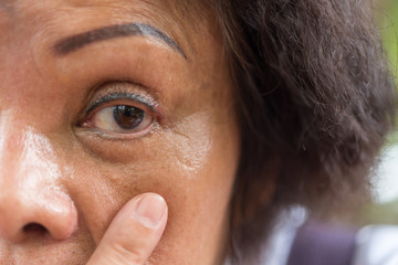 Asian elder women show her eyes and eyebrow tattoo