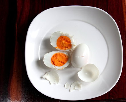 Boiled duck egg on a white plate on the wooden floor.