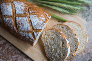 Bread slice on a wooden board. Wheat fresh loaf