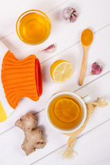 Hot water bottle, cup of tea and ingredients for preparation warming beverage for winter evening