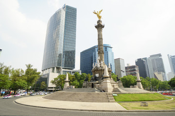Marble column with golden monument in form an angel girl on top at background of skyscrapers in...