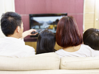 asian family with two children watching TV together