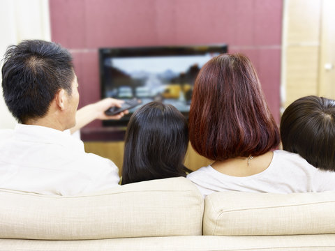 Asian Family With Two Children Watching TV Together