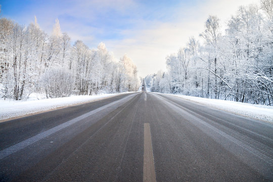 winter landscape with asphalt road,forest and blue sky.