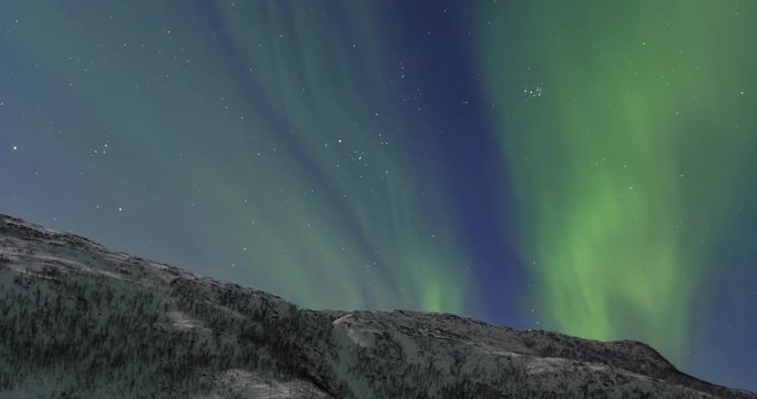 Northern Lights, polar light or Aurora Borealis in the night sky time lapse over Senja island in Northern Norway.