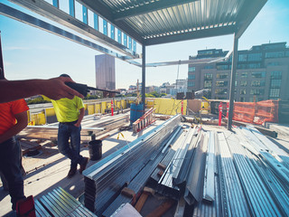 men at construction site talking with steel in foreground © maxwellmonty