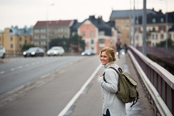 A woman traveler with backpack on a street in a European city