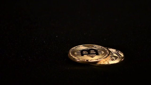 Gold Bitcoin rotates on a black background. Slow motion