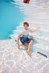 young woman in blue and white dress swim and dive underwater floating pool with transparent water in Beautiful Mysterious Underwater World. Fantastic Fairy dreamy fashion. Water safety class