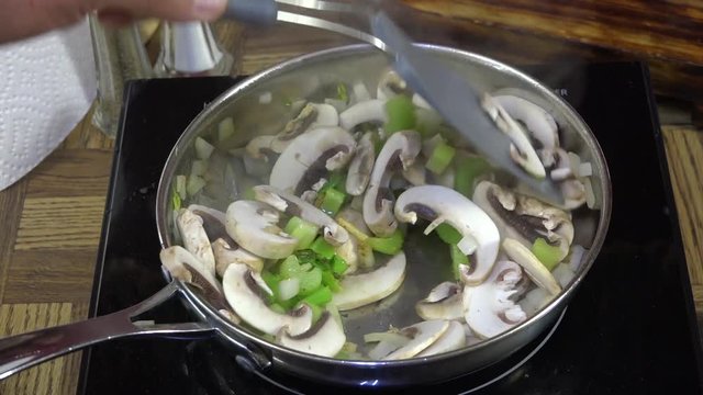 Sauteing mushrooms, celery and garlic in a frying pan
