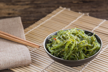 wakame seaweed salad in a ceramic dish on bamboo mat. popular and delicious japanese food appetizer.