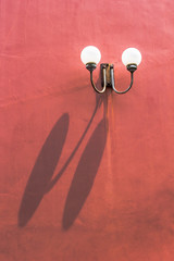 Two llight on red wall with shadow