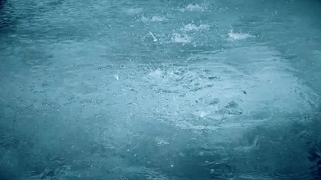 slow motion of heavy rain water drops or foutain on surface street, seamless loop ready