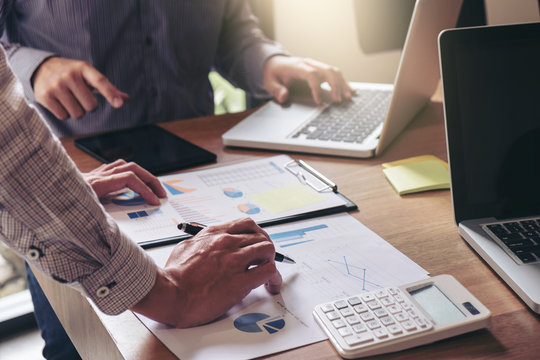 Teamwork process, Business team two managers colleagues discussing and analysis new plan financial graph data and marketing documents report on office table with laptop and digital tablet - Powered by Adobe