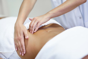 Obraz na płótnie Canvas Woman receiving a belly massage at spa salon