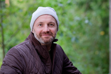 Naklejka na ściany i meble handsome mature man smiling in warm hat and jacket looking at camera