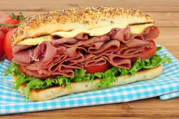 Spicy pastrami meat and salad sandwich in a seed covered bread roll isolated on a white background