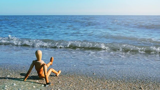 	The wooden little man (dummy) on the beach.