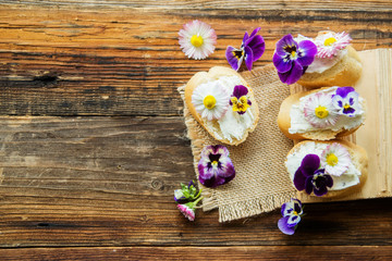 Sandwich with herb and edible flowers butter on marble cutting board. Healthy food.