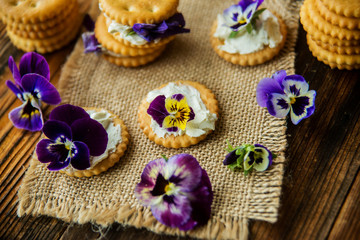 Sandwich with herb and edible flowers butter on wooden background, healthy food.