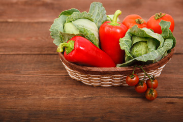 Basket with fresh vegetables on a wooden table. Tomatoes, Bulgarian pepper and cabbage.