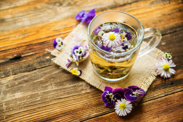 Obraz na płótnie Canvas Cup of tea with chamomile flowers on rustic wooden background