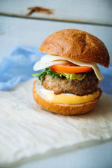 Tasty burger with beef with spinach and blue cheese served on a small board on a wooden background.