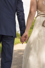 Hochzeitspaar von hinten hält sich an den Händen 