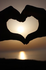 Fototapeta premium Cuore realizzato con le mani con il tramonto