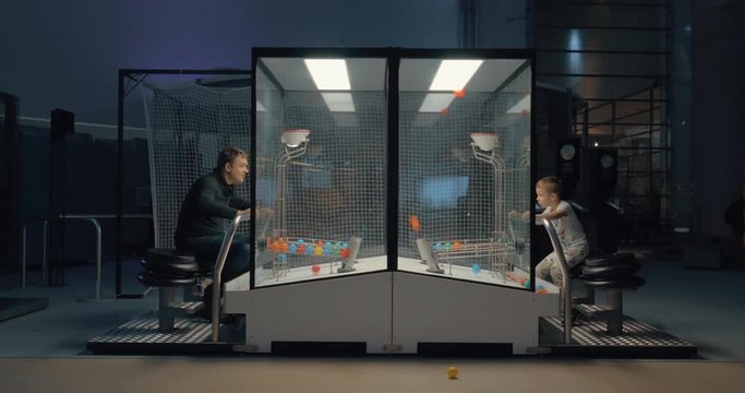 Cinemagraph - Dad and son having fun with attraction in indoor amusement park. They playing ball game trying to score each other