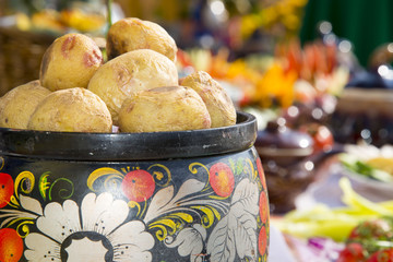 Baked whole potatoes in a pot, painted in Russian folk style.Table with food decorated in Russian folk style.