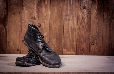 Old leather boots on dirt wooden background  