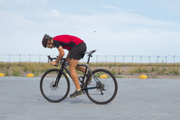 Professional bicycle rider in helmet and sportswear training on empty road  