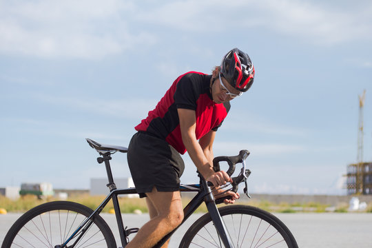 Professional bicycle rider in helmet and sportswear training on empty road  