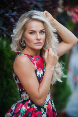 Portrait of a beautiful blonde in dress in flowers