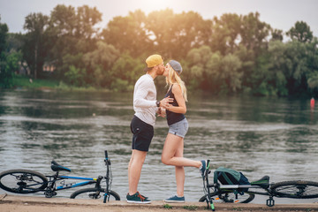 Romantic Couple with Bikes Relaxing at Sunset by the Lake. Fall in Love Concept.