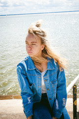 young beautiful woman in jeans clothes outdoors. portrait of a girl with freckles on her face, stylish girl on sea beach, on a sunny summer autumn day.