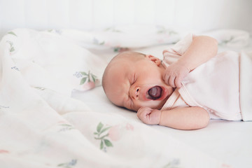 Newborn baby girl sleeps and yawning.