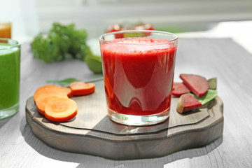 Glass of fresh smoothie and sliced vegetables on wooden board