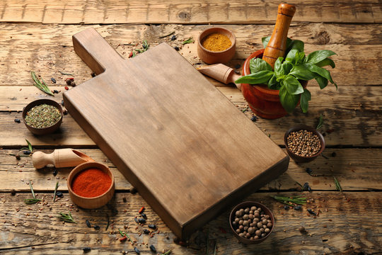 Composition with cutting board, spices and herbs on wooden background