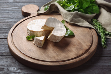 Wooden board with soft cheese on table